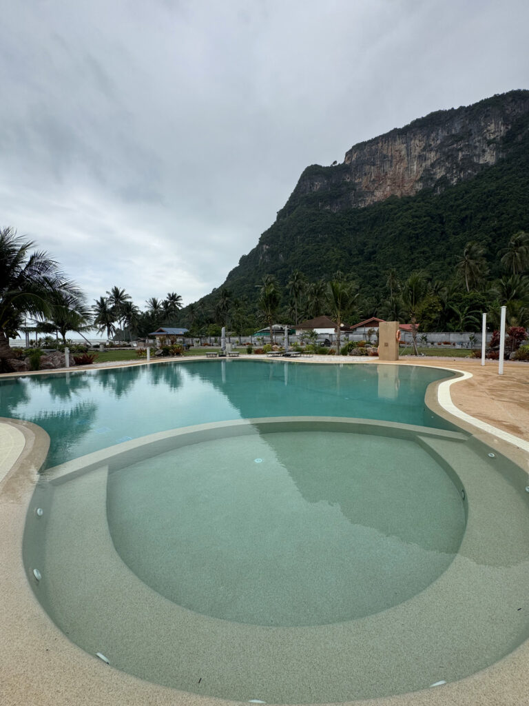 Round submerged seating area joining the main pool at This Great Place Resort, with mountains and palms beyond.