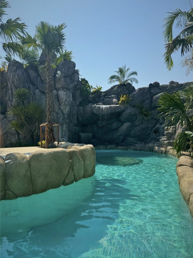 Lagoon pool with curved edges and a waterfall set into the rockwork beyond.