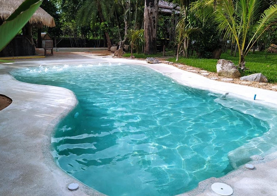 Freeform lagoon pool with curved submerged steps and a tropical garden in Eastern Thailand.