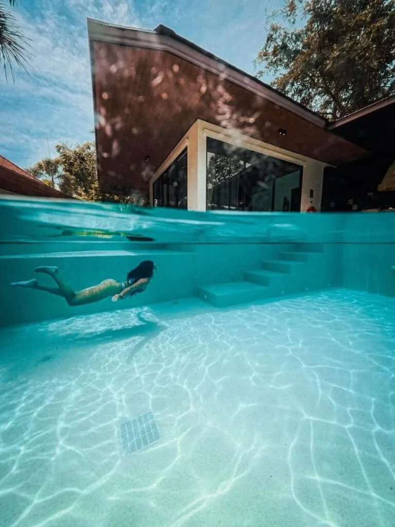 Split-level view of a Polar White pool, submerged steps and a swimmer at a private villa in Phuket