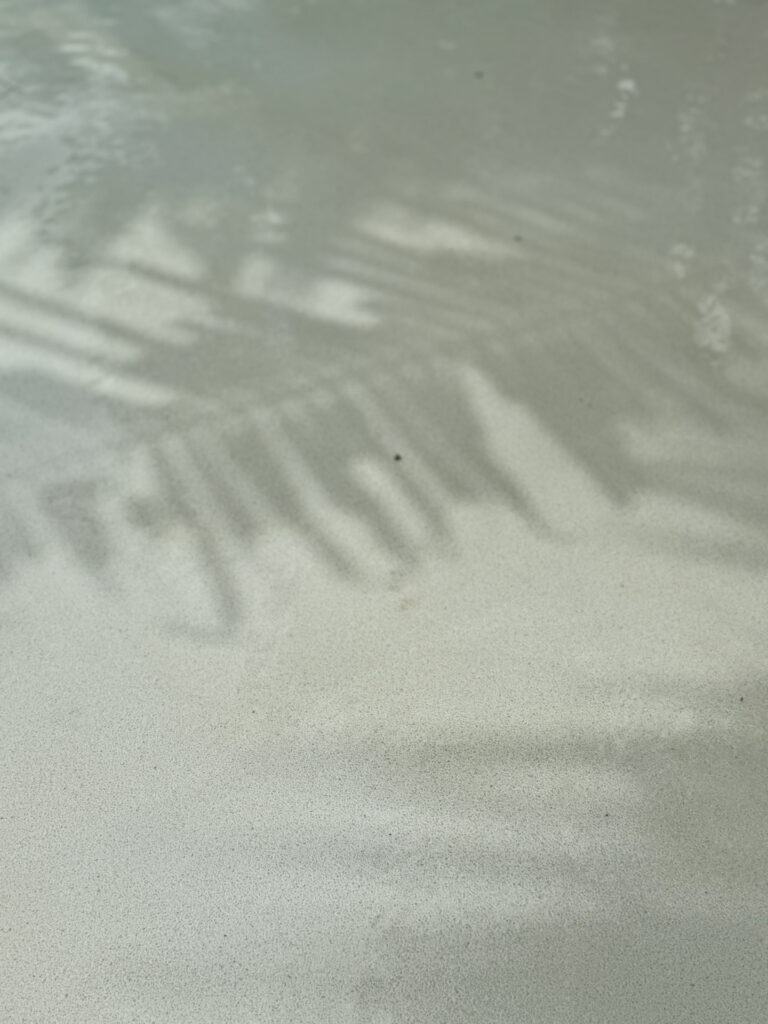 Close-up of Pearl White aggregate finish under gently rippling water at The Talay.